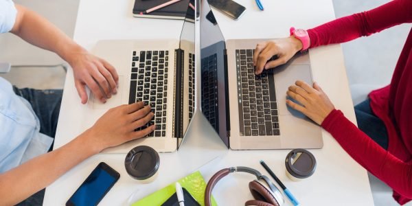 view from avove on hands of young man and woman working at laptop in co-working office, typing on keyboard, table work place, startup team of freelancers